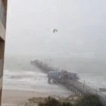 kite surfer jumps over pier