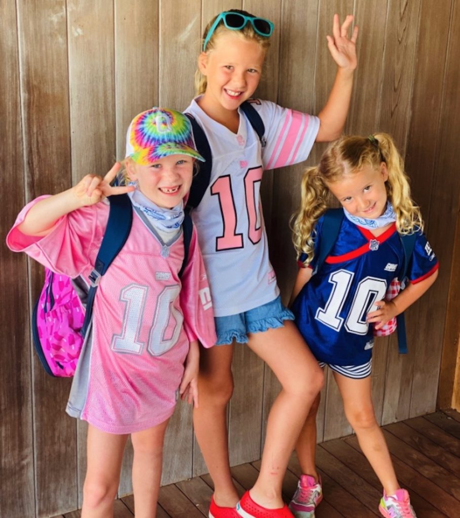 A photo of Eli Manning's three daughters smiling for the camera and waving.