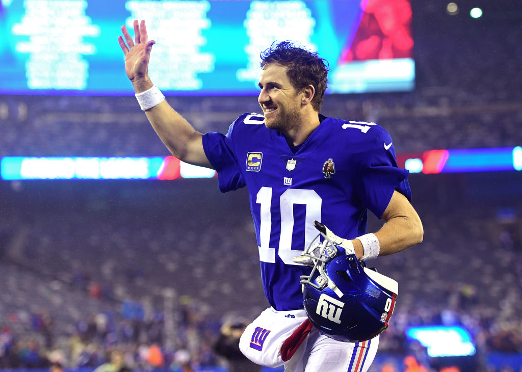Eli Manning wearing New York Giants number 10 jersey waiving and smiling to fans.