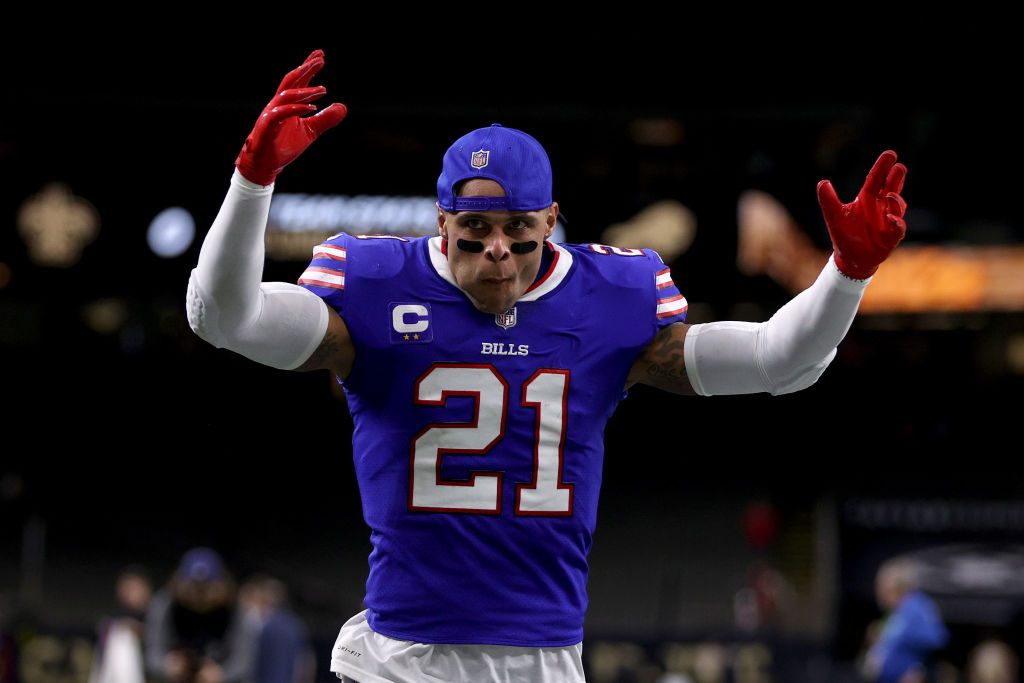 Jordan Poyer in a backwards hat throws his hands up in the air wearing a number 21 Bills jersey after a win