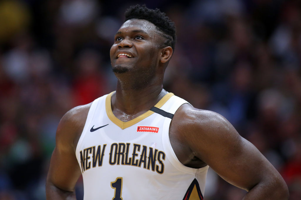 Zion Williamson smiling and looking up in the middle of a New Orleans Pelicans basketball game, with sweat running down his face.