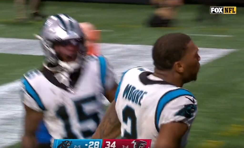 Panthers wide receiver D.J. Moore celebrates a touchdown with his helmet off.