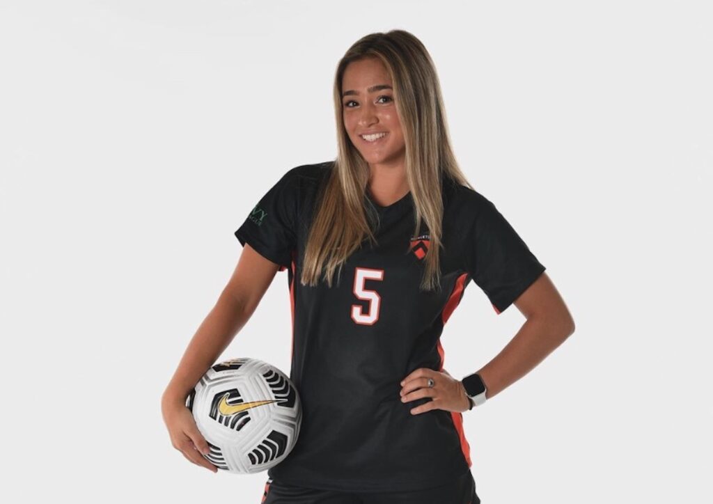 Amy Paternoster wearing her Princeton soccer uniform and holding a soccer ball.