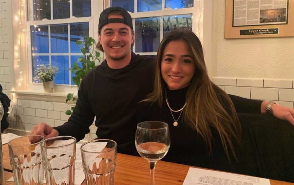 Kenny Pickett and girlfriend Amy Paternoster smiling at a restaurant, both wearing black.