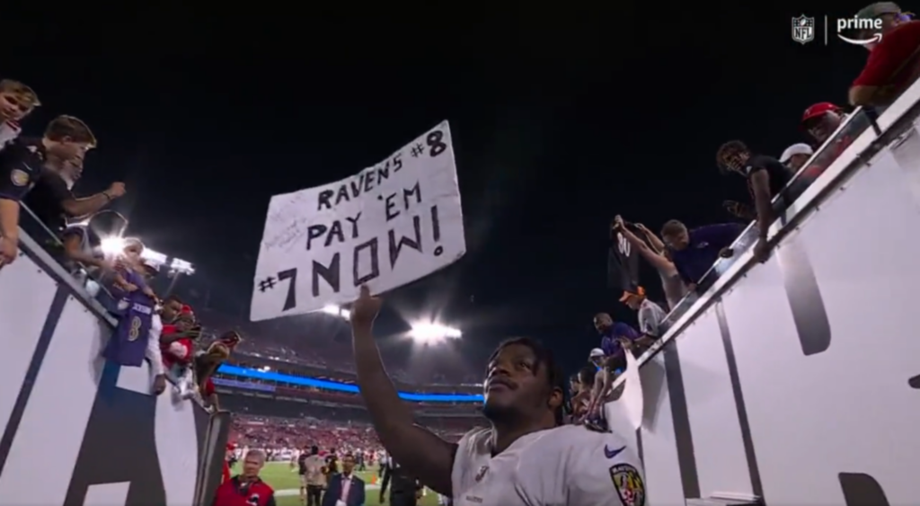Lamar Jackson Holds Up Sign That Says To "Pay" Him
