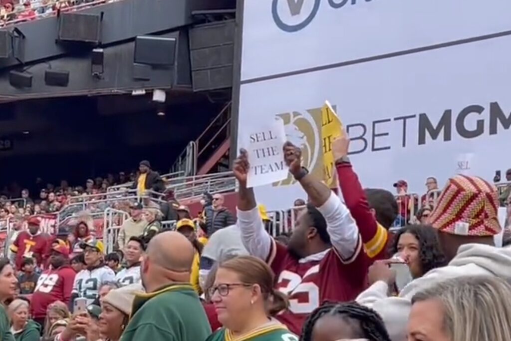 Washington Commanders fan holds up "Sell the Team" sign.