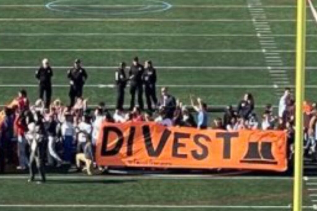 Protesters seated on football field interrupting game
