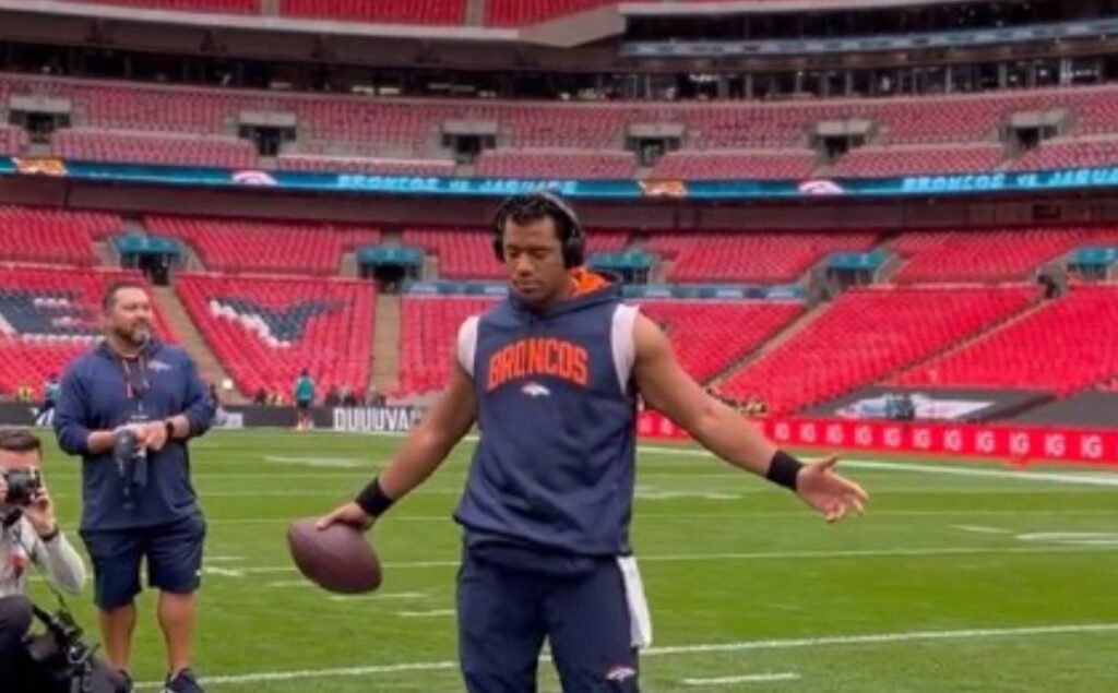Russell Wilson with his arms out praying