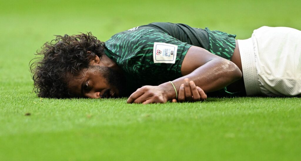 Saudi Arabia's Yasser Al-Shahrani lays unconscious on the pitch.