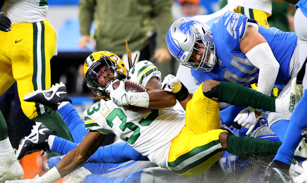 Packers running back Aaron Jones gets tackled by Lions defenders.