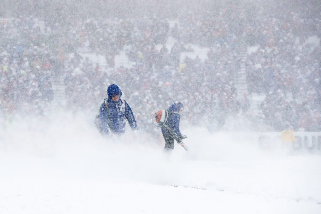 Workers blow snow off the field during Buffalo Bills game.