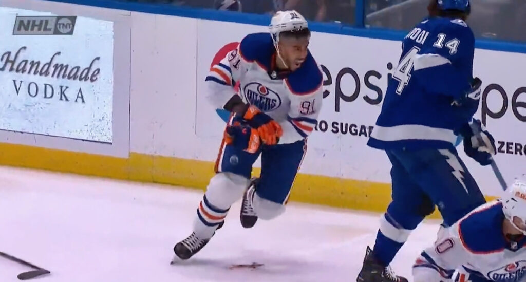Oilers Evander Kane holds his bleeding rist after being sliced by skate and skates to the bench.