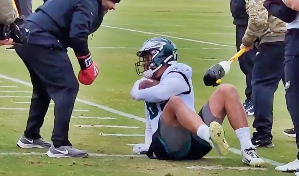 eagles player on ground with ball, man stands over him with ball