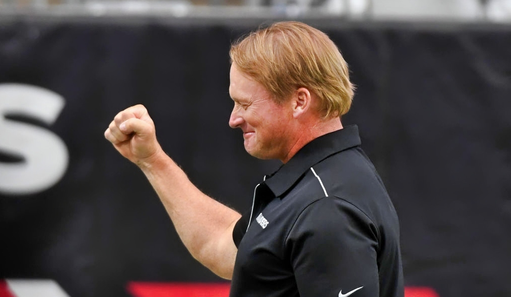 Jon Gruden holds out his fist while smiling
