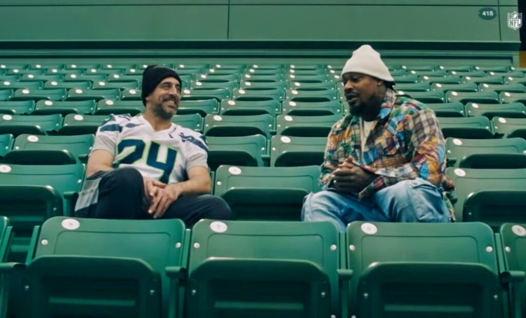 Aaron Rodgers and Marshawn Lynch sitting in the stands