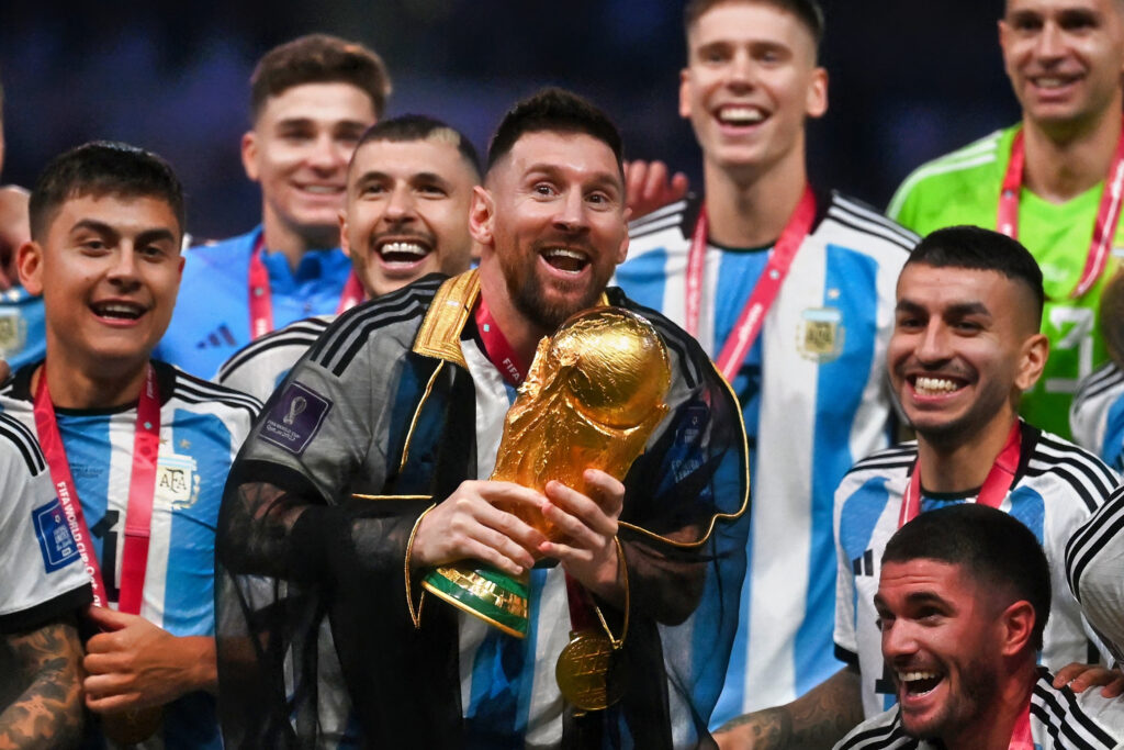 Lionel Messi with team holding the world cup trophy.