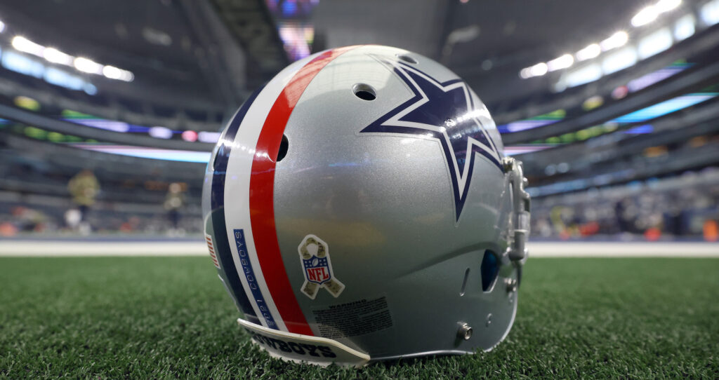 A Dallas Cowboys helmet with the red, white and blue stripe is positioned on the field.