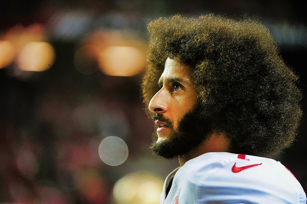 Colin Kaepernick in uniform while rocking an afro