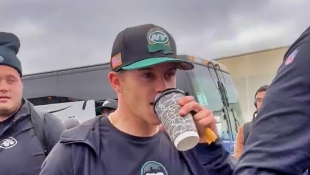 Jets player drinks a coffee while wearing Mike White shirt.