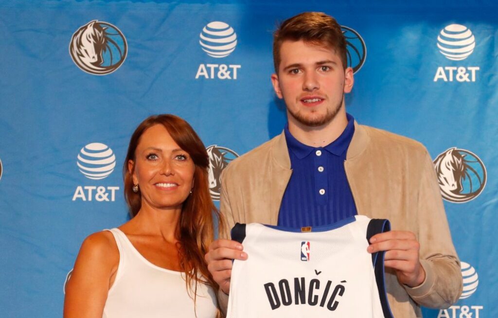 Luka Doncic holding Mavs jersey while standing next to his mother