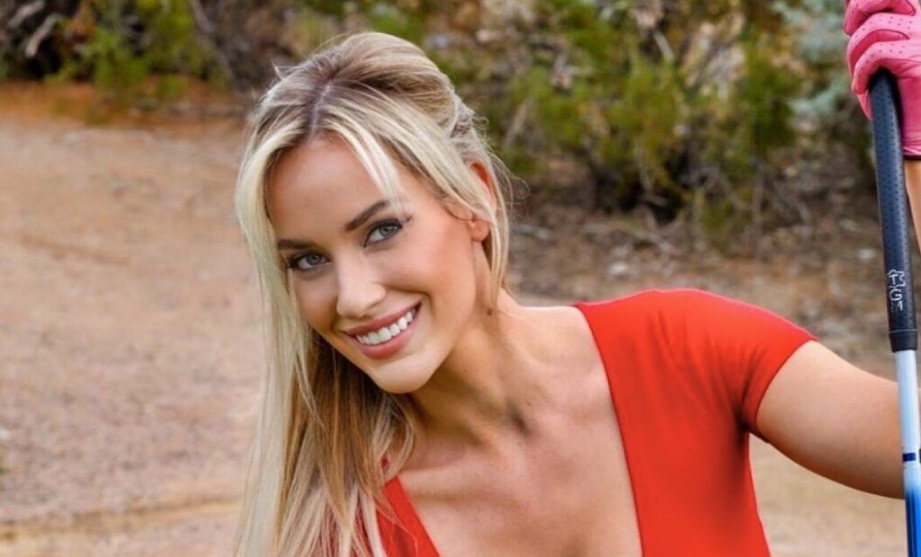 Paige Spiranac posing for picture with golf club in hand