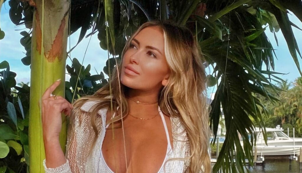 Paulina Gretzky posing in white outfit by trees