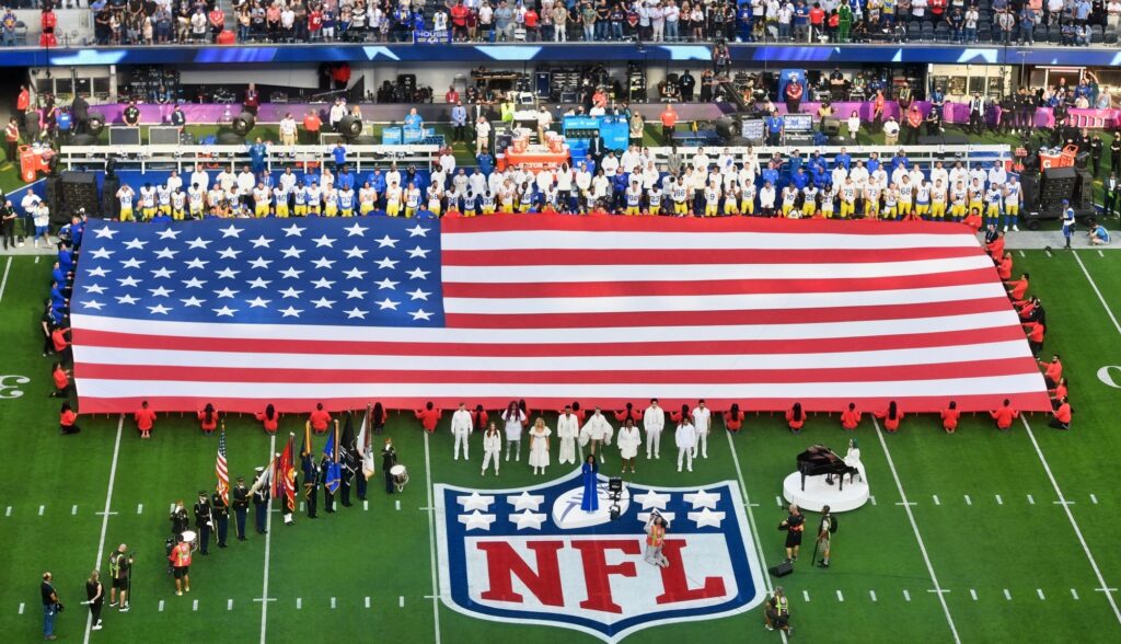 Giant USA flag appears on an NFL field before the Super Bowl.