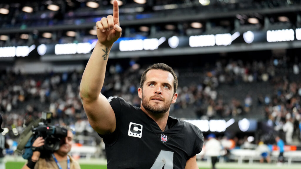 Derek Carr points to the sky with his helmet off after a game.