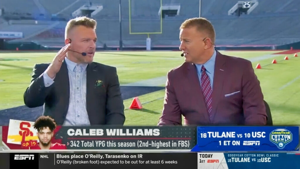 Kirk Herbstreit in a suit while sitting at desk on field