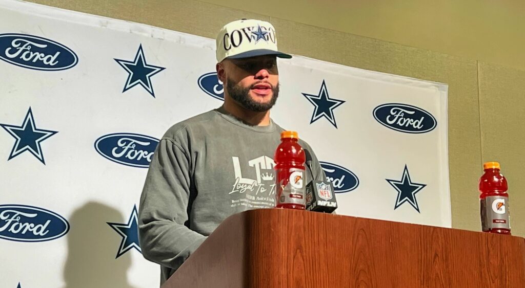 Dallas Cowboys quarterback Dak Prescott speaking to reporters at a podium.