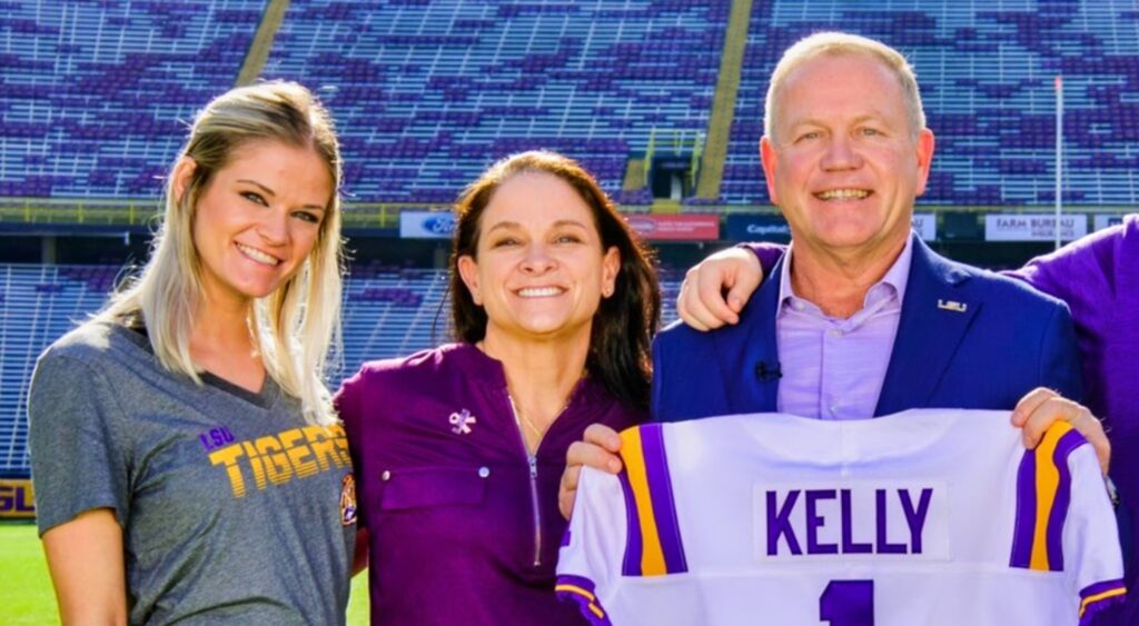 LSU Coach Brian Kelly poses with his wife and daughter on the field.