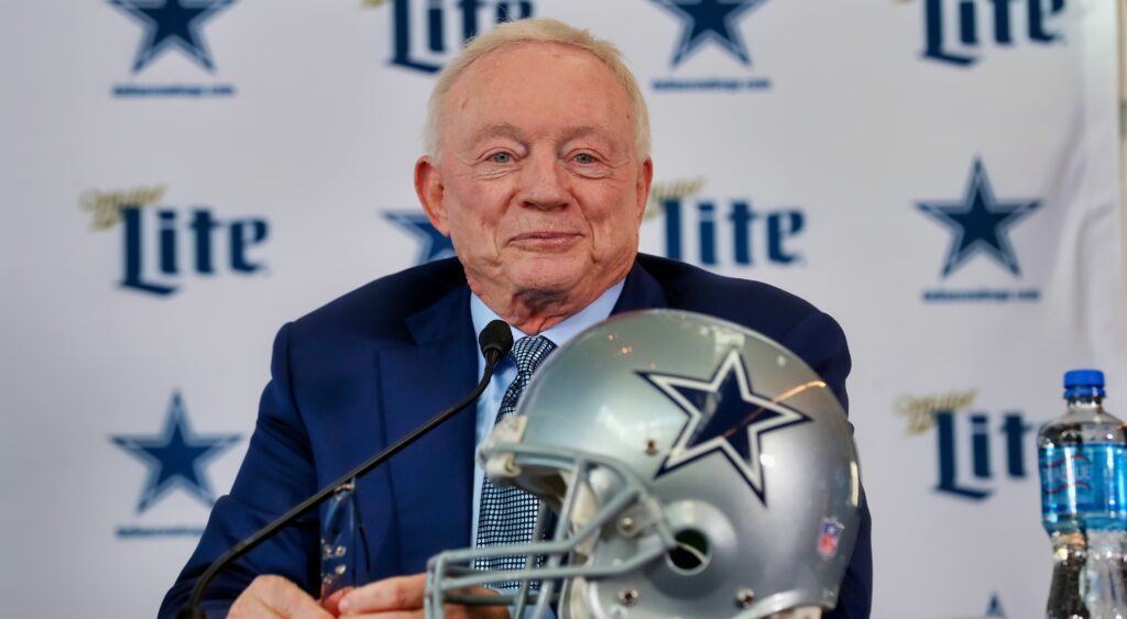 Jerry Jones at a press conference table behind a Cowboys helmet.