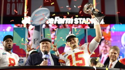 Terry Bradshaw standing next to Patrick Mahomes as he lifts the Lombardi Trophy