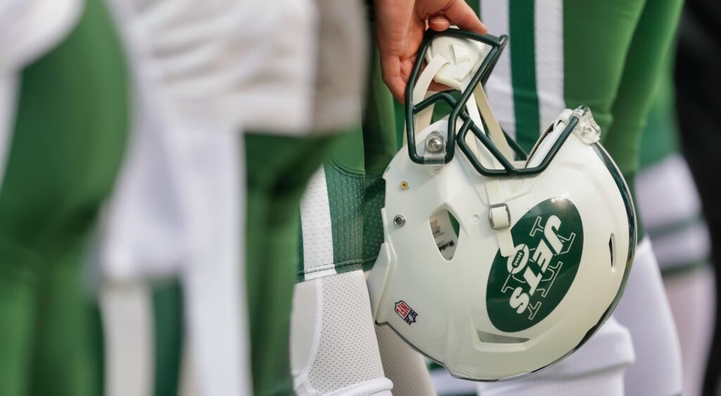 A Jets players holds his helmet by his side.