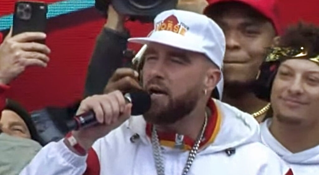 Kansas City Chiefs tight end Travis Kelce speaking with microphone in hand at team's Super Bowl 57 parade.