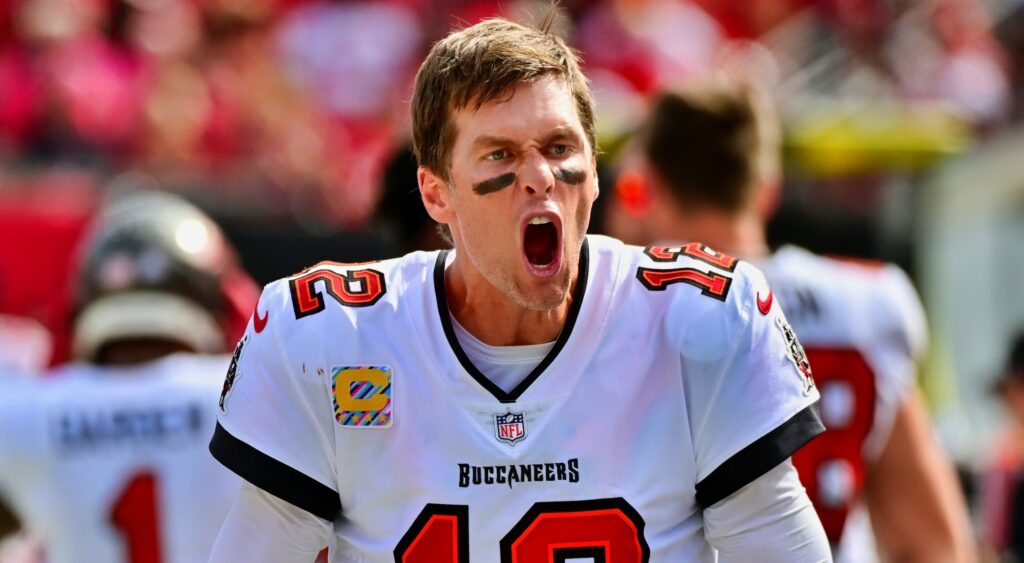 Tom Brady yells during a game with his helmet off.
