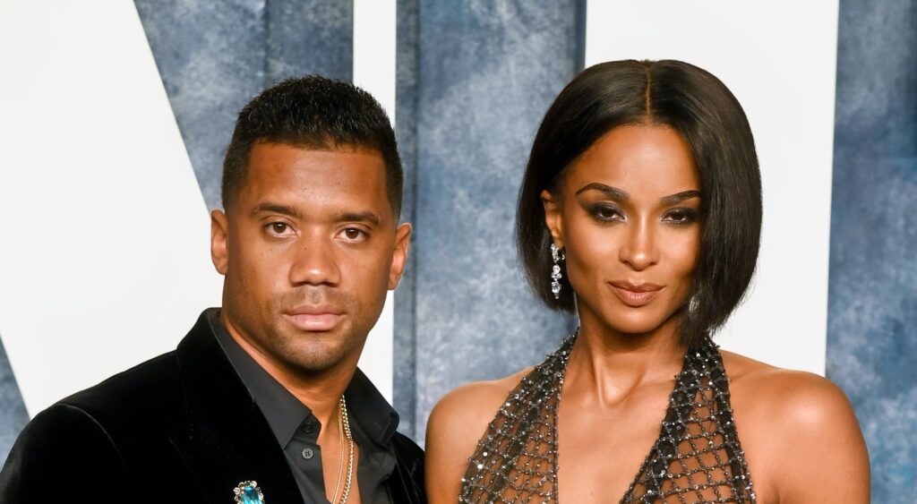 Russell Wilson and Ciara posing in suit and dress