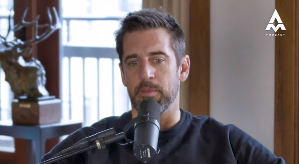 Aaron Rodgers sitting with mic in front of him on podcast