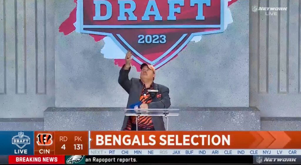 Cincinnati bengals fan throws a coin into the air at the podium during the NFL Draft.