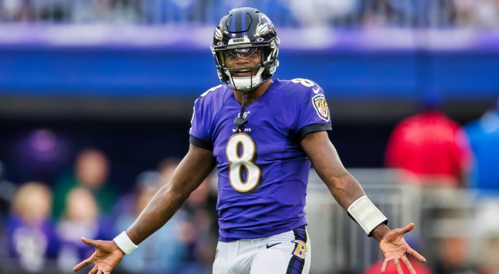 Lamar Jackson holds out his arms during a game.