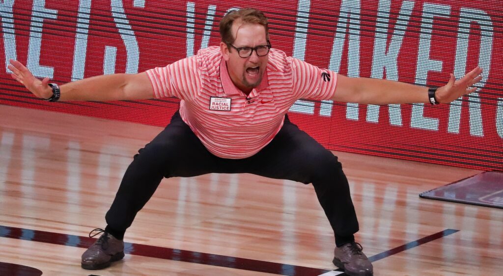 Nick Nurse holds out his hands on the court during a game.