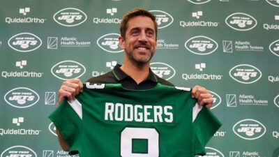 Aaron Rodgers holding up his new Jets Jersey