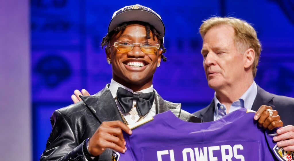 Ravens first round pick Zay Flowers hold up his jersey alongside Roger Goodell at the draft.
