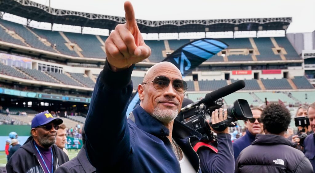 The Rock points out to the stands while on the field at an XFL game.