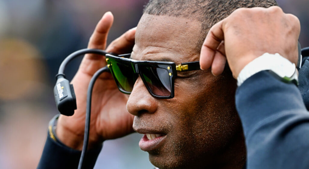 Deion Sanders with glasses on and headset.