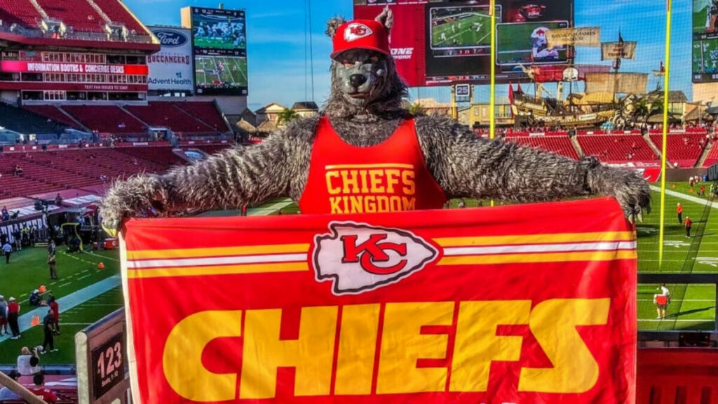 Kansas City Chiefs' superfan "ChiefsAholic" holding flag in wolf outfit.