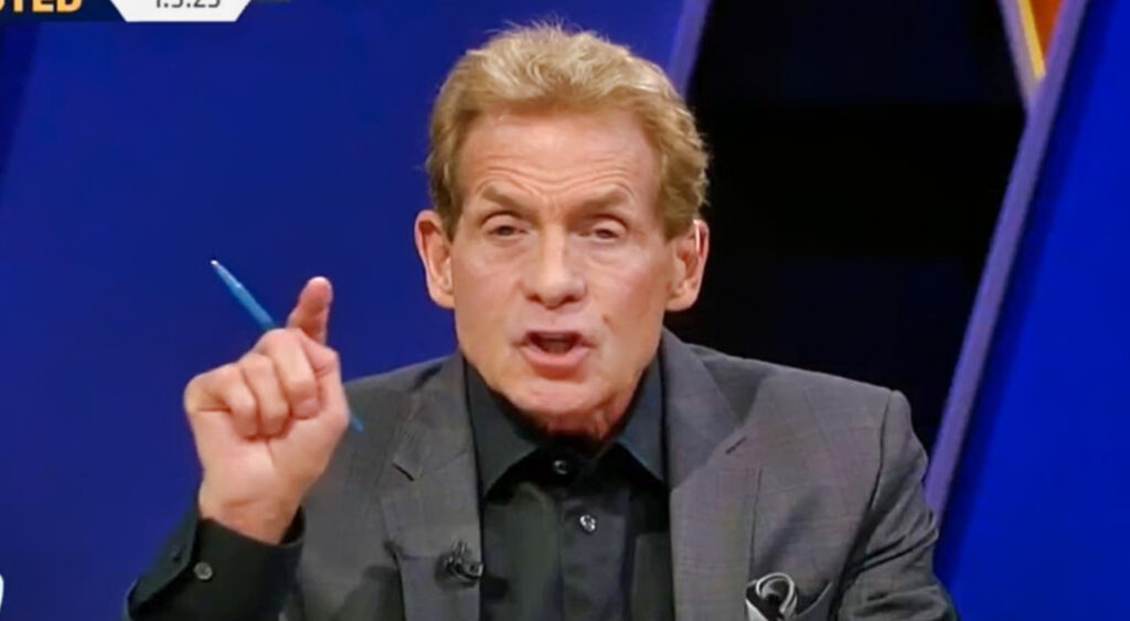 Skip Bayless in suit and pointing