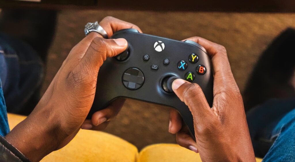 A man's hands playing with an Xbox controller.