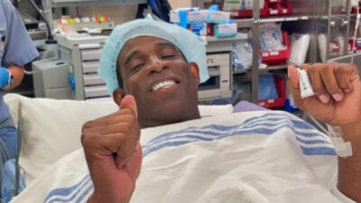 Deion Sanders smiling in a hospital bed