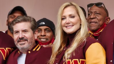 Dan Snyder smiling with wife and others with Commanders gear on